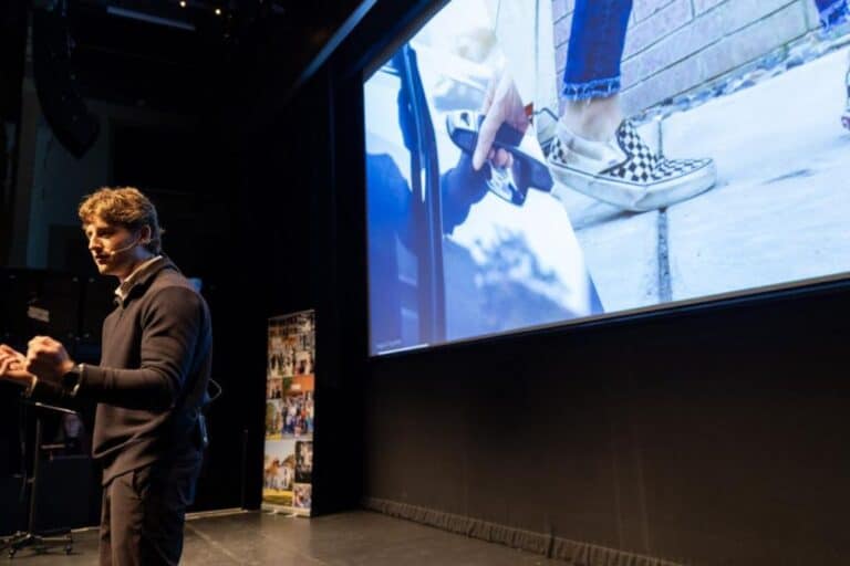 Student speaks on stage with screen in the background